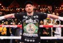 Oleksandr Usyk with his arms outstretched and 'Egypt 23.5.26' written on his right hand and 'winner' written on his left hand
