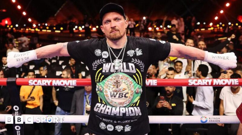 Oleksandr Usyk with his arms outstretched and 'Egypt 23.5.26' written on his right hand and 'winner' written on his left hand