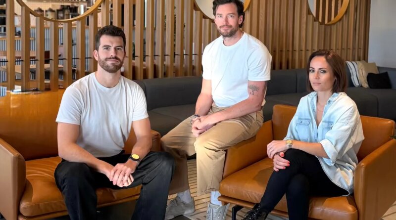 Two men and a woman sit on leather chairs in a well appointed office space.