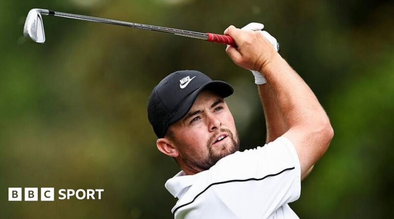 Alex Fitzpatrick watches his ball after playing an iron shot, with the club above his head