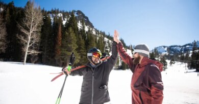 Two friends high-fiving while skiing.