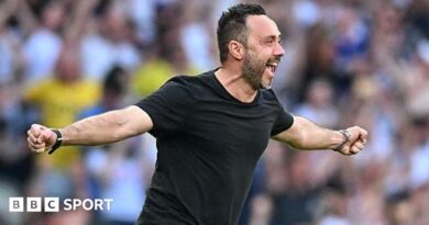Roberto de Zerbi celebrates with a broad smile and arms outstretched as he runs on to the pitch in a black T-shirt