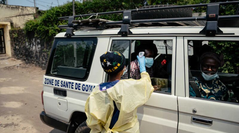 A person uses a digital thermometer on a passenger in a van.