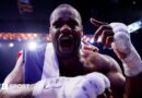 Daniel Dubois leans over the ropes of a boxing ring and holds up his hand
