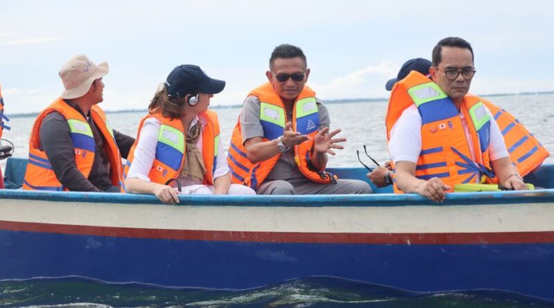 Indonesian diplomat Tri Tharyat sits in a boat with other officials wearing life jackets on the water.