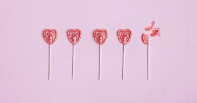 Five lollipop hearts on a pink floor, but the last one is smashed to pieces.