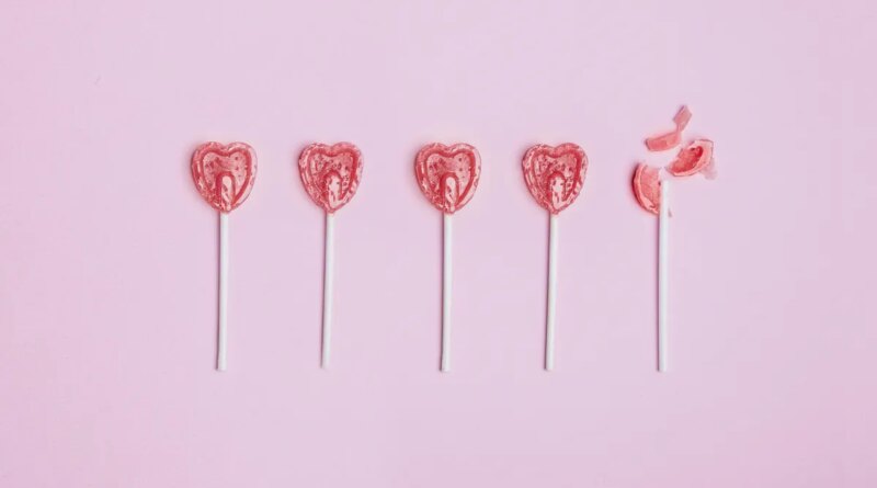 Five lollipop hearts on a pink floor, but the last one is smashed to pieces.