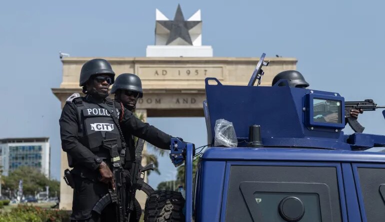 Members of Ghana security forces take part in a joint Show of Force Exercise in Accra, Ghana, 11 December 2025. The exercise featured the Ghana Police Service, Ghana Prisons Service, Ghana National Fire Service, the Customs Division of the Ghana Revenue Authority and the Immigration Service in collaboration with the Ghana Armed Forces, aimed at Police officers on security detail near a police vehicle, with the Ghana Black Star atop a building behind them. [FRANK KPORFOR/Epa]