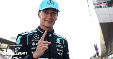 George Russell looks at the camera and points his index figure upwards
