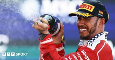 Lewis Hamilton crossing the line with Novak Djokovic waving the flag