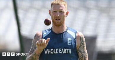 Ben Stokes, wearing a blue England vest, tosses a ball in the air