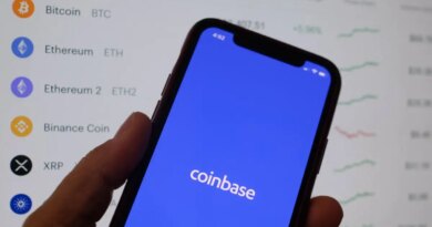 Coinbase's logo on a phone in front of crypto prices
