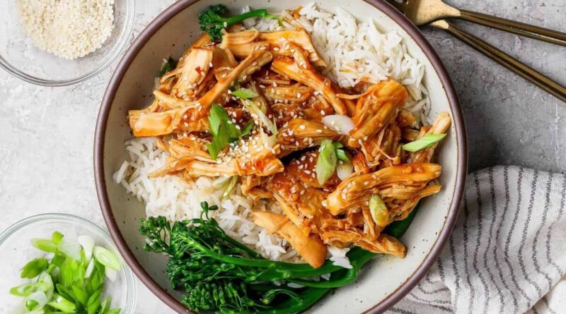 Crockpot honey garlic chicken served over white rice with broccolini in a bowl
