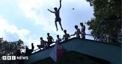 A person jumps off a bridge into the Canal Saint-Martin as public swimming having been allowed earlier on part of it due to rising of temperatures