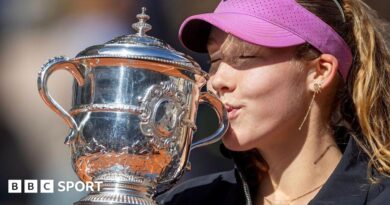 A close-up of Mirra Andreeva's jacket bearing the phrase 'I want to thank myself' while she holds the French Open winners' trophy