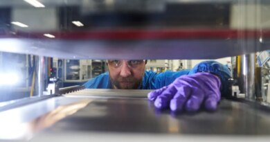 A man reaches his hand into a machine to grab a battery prototype.