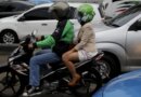 A Gojek driver pillions a customer as he rides his motorcycle through a business district street in Jakarta