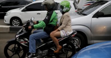 A Gojek driver pillions a customer as he rides his motorcycle through a business district street in Jakarta