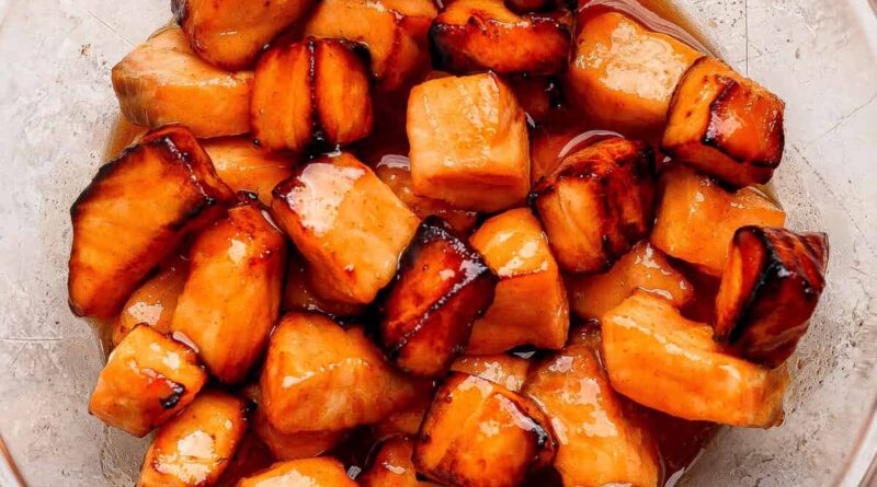 Cubes of cooked salmon in a glass bowl, coated with a shiny, dark caramelized glaze.