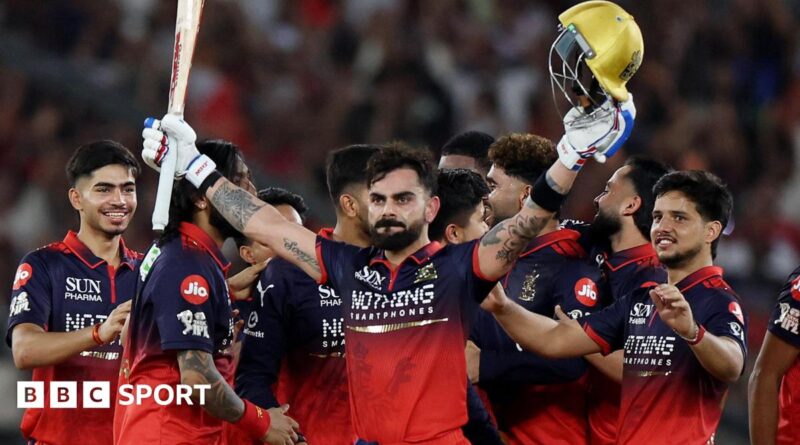 Virat Kohli holds his bat and helmet aloft as his RCB team-mates celebrate winning the IPL