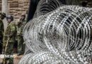  Coils of razor wire are stacked outside a government building as armed security officers stand guard