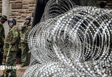  Coils of razor wire are stacked outside a government building as armed security officers stand guard