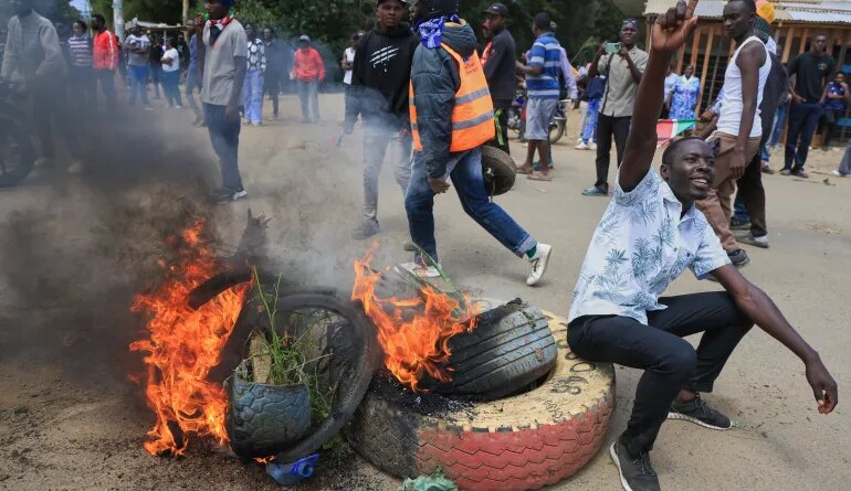 A protester gestures beside a burning barricade during a demonstration against a proposed Ebola quarantine center to be established by the United States at Laikipia Air Base in Nanyuki, Kenya, Monday, June 1, 2026. (AP Photo/Andrew Kasuku)