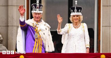 King Charles and Queen Camilla on the Buckingham Palace balcony wearing crowns and robes
