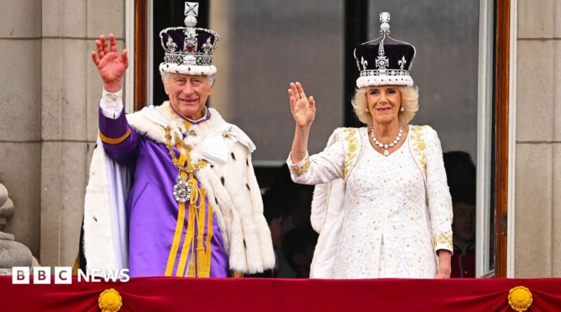 King Charles and Queen Camilla on the Buckingham Palace balcony wearing crowns and robes