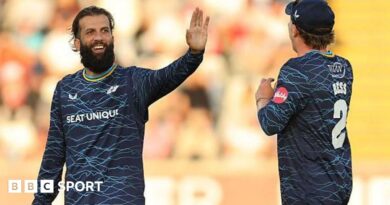 Yorkshire player Moeen Ali smiles and holds up his hand in celebration as he is approached by team-mate Dom Bess.