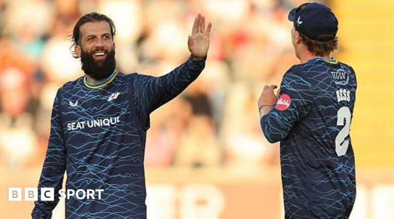 Yorkshire player Moeen Ali smiles and holds up his hand in celebration as he is approached by team-mate Dom Bess.