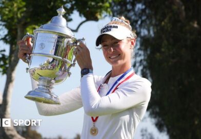Nelly Korda, wearing a long-sleeved white top and white visor and with a gold medal on a red, white and blue ribbon around her neck, smiles and poses with the silver trophy, holding it up to her right