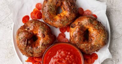 Three pizza protein bagels on parchment paper served with marinara sauce and pepperoni
