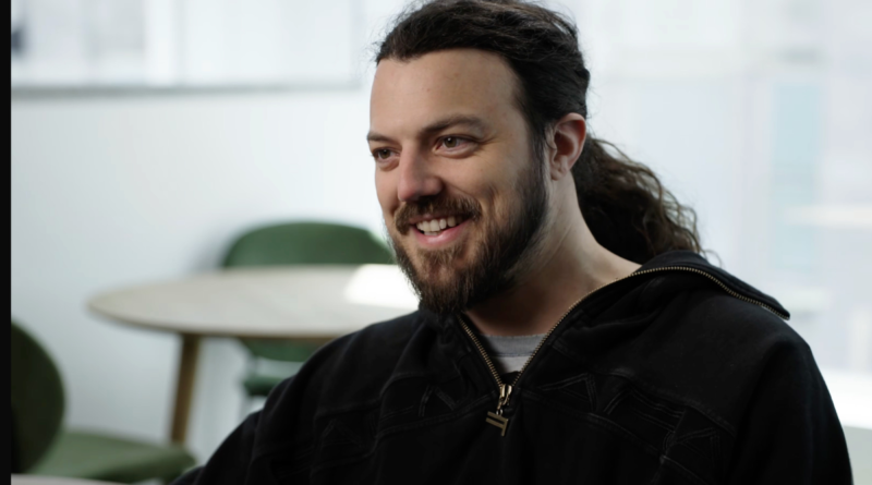 A caucasian man with long dark hair and a full beard