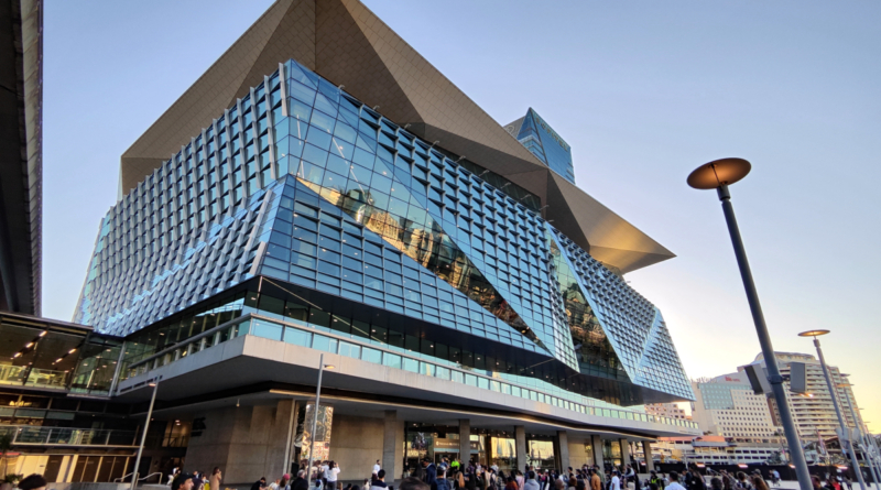 Sydney modern skyline viewed at Darling Harbor. People walking on the pedestrian zone in central Sydney.