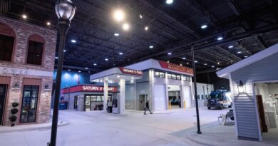 a screenshot from the FBI's Kinetic Cyber Range video, showing the FBI's model town cross walk, including a business center, and a light post, inside a large warehouse space.