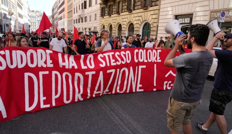 People hold a banner in Italian reading "Skin and sweat have the same color, no deportation' during a march in Rome, Saturday, June 13, 2026, to protest Italy's security and migration package, including a migrant "repatriation bonus" scheme criticized by opposition parties and legal groups as unconstitutional and ethically problematic. (AP Photo/Gregorio Borgia)