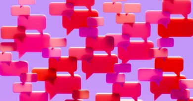Conceptual image of a dense cluster of three-dimensional speech bubbles in shades of pink red and magenta overlapping and filling the visual field against a solid vibrant purple background.