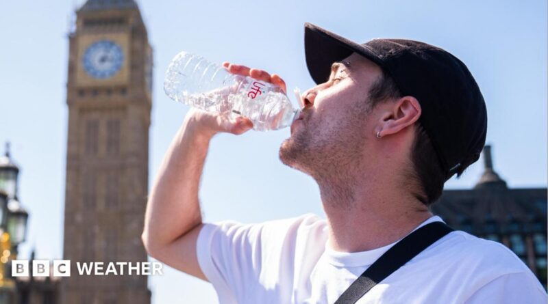 A man drinks from a water bottle with a sunny sky overhead and a blurred view of the Westminster skyline in the background