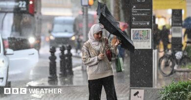 A woman tries to reverse her inside out umbrella in rainy conditions