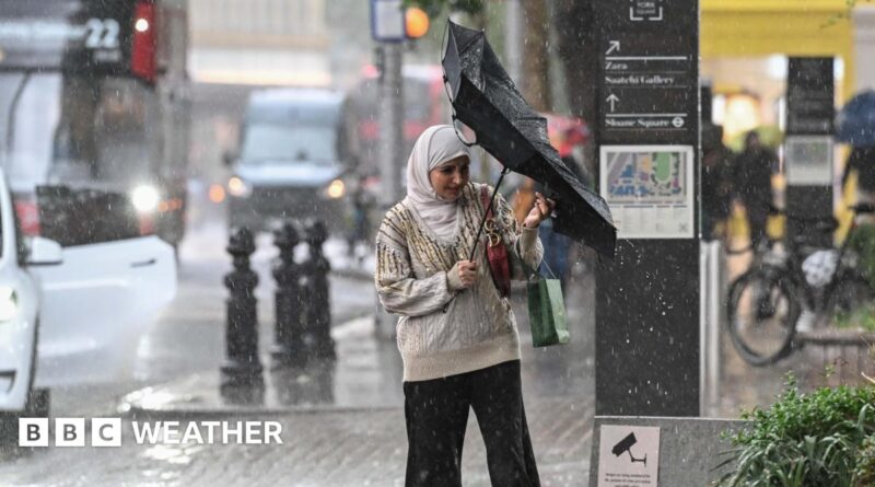 A woman tries to reverse her inside out umbrella in rainy conditions