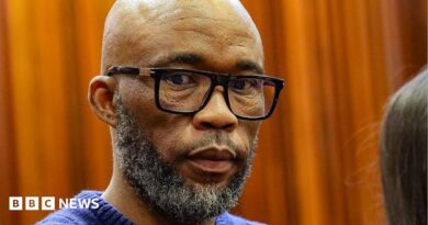 A head and shoulders picture of Cat Matlala in court - he is wearing a blue jumper, the neckline of which can just be seen at the bottom of the picture.
