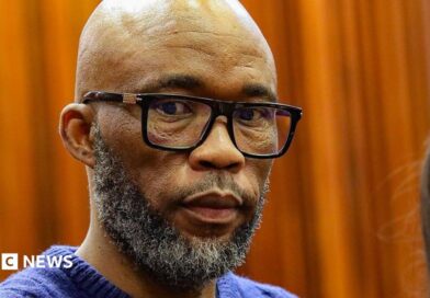 A head and shoulders picture of Cat Matlala in court - he is wearing a blue jumper, the neckline of which can just be seen at the bottom of the picture.