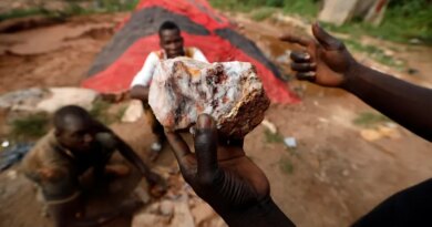 An informal gold miner holds up a rock recovered from inside a gold mine before it is ground down for processing at the site of Nsuaem-Top, Ghana