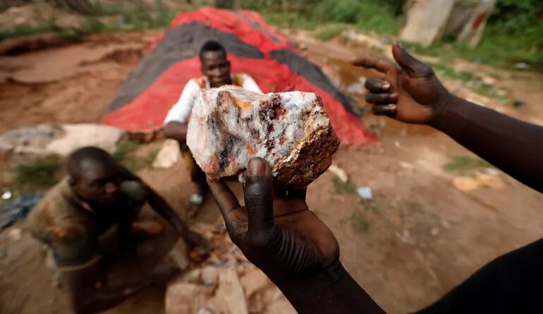 An informal gold miner holds up a rock recovered from inside a gold mine before it is ground down for processing at the site of Nsuaem-Top, Ghana