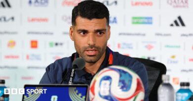 Mehdi Taremi speaks into a microphone while conducting a press conference