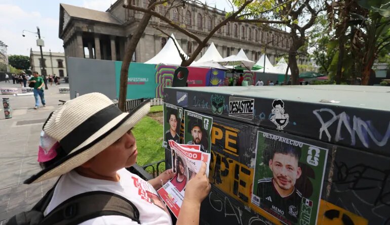 A member of the Colectivo Luz de Esperanza de Jalisco collective holds missing-person flyers near pasted signs featuring images of their loved ones who remain missing, displayed in a World Cup-style format, as part of the “Missing Persons World Cup Album" campaign to raise awareness of disappearances ahead of the 2026 FIFA World Cup, in Guadalajara, Mexico, May 31, 2026.  REUTERS/Michelle Freyria TPX IMAGES OF THE DAY