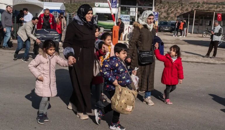 CILVEGOZU, TURKEY - DECEMBER 13: Syrian families living in Turkey walk towards the Cilvegozu border gate to cross into Syria after after Syrian rebels ousted President Bashar al-Assad on December 13, 2024 in Cilvegozu, Turkey. The fall of the Assad regime last week has prompted many Syrians in neighboring Turkey to try to reenter their home country. Turkey hosts a population of more than 3 million Syrian refugees, according to UNHCR statistics. (Photo by Burak Kara/Getty Images)