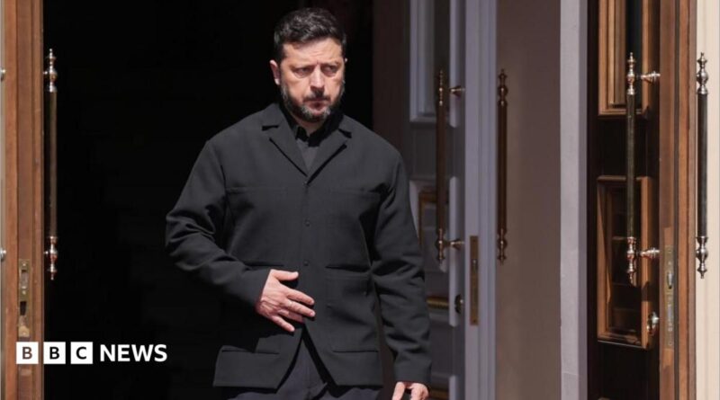 Zelensky, wearing a dark suit, walking through a doorway