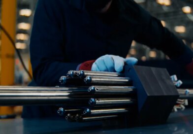 A person handles a nuclear fuel assembly.